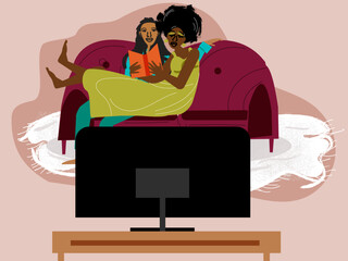 Lesbian couple cuddling on the couch watching tv while partner reading book 