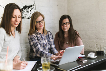 Students working together sitting on table in a coffee shop