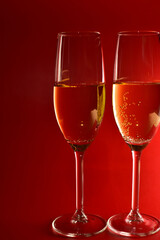 Elegant glasses with champagne on red background