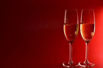Elegant glasses with champagne on red background