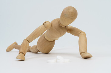The wooden man crawls for pills. Isolated on white background.