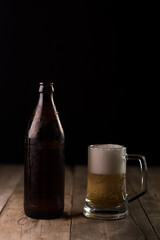 Bottle of craft beer and beer mug on a wooden table