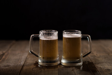 Two beer mugs at a wooden table