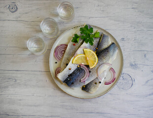glass of vodka, herring on a wooden background