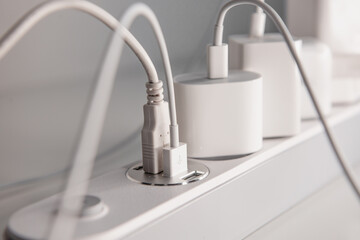 Many chargers plugged into maltiple electrical outlet on white background. Concept of electricity...