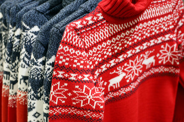 Knitted sweaters with Christmas pattern in a store. Traditional warm outfit for New Year holidays
