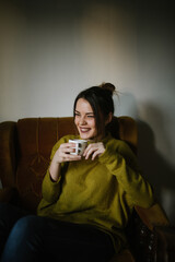 Young woman holding a mug in an armchair