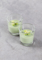 Avocado cream jelly in a glass on a light gray background