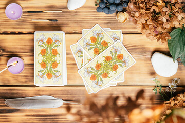 Tarot cards spread face down on wooden surface with candles, stones, autumn plants. Minsk, Belarus, 11.10.2021