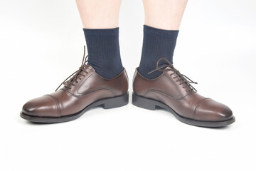 Male legs in socks and brown classic shoes on a white background