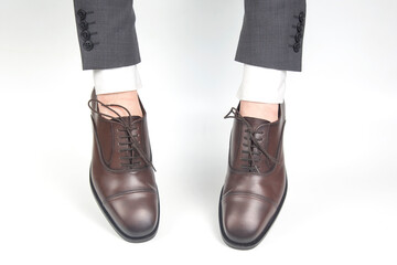 Classic brown shoes worn on the hands on a white background