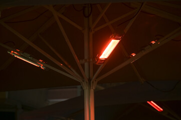 Heat lamps under an umbrella in a street cafe at night, because under 2G rules only vaccinated and...
