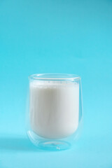 Milk in double glass insulate glass on blue minimal background. Lactose free milk made of vegan ingredients. Source of calcium