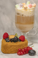 Breakfast with cup of latte decorated with marshmallows and delicious cace decorated with fresh blueberries, rospberries and brush red currant