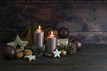 Christmas decoration in dark rose and brown with candles balls, cones and stars agains a rustic wooden background, copy space, selected focus