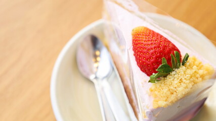 Strawberry shortcake on a plate. Delicious cream and strawberry cake on brown wooden floor with copy space. Choose to focus on the subject closely.