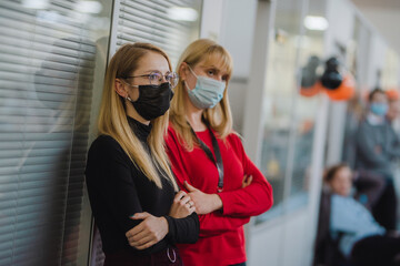 Two women wearing medical masks in office