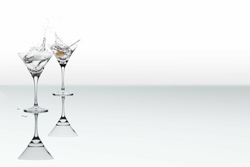 A pair of cocktail glasses with a splash of a drink and a single olive on a stick