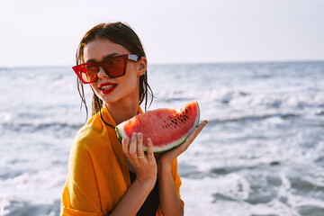 woman on the beach near the ocean eating watermelon