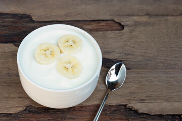 Fruit yogurt has banana and honey greek white clean In bowl on a wooden background from top view.
