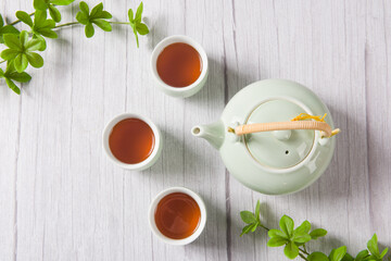 black tea with tea cups and teapot, with green leaves. 
