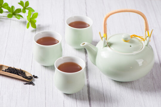 black tea with tea cups and teapot, with green leaves. 