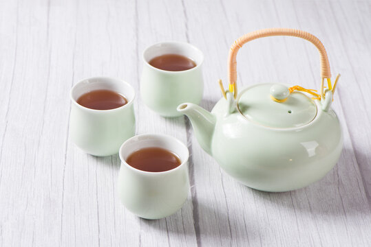 black tea with tea cups and teapot, with green leaves. 