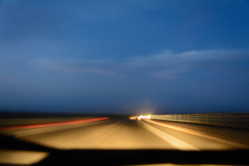 Long exposure on road with speed of light inside the car at sunset with cloudy sky. Light from the...