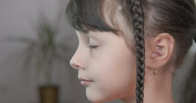 Stay at home with a pigtail. A cute child stay with a pigtail in the room.