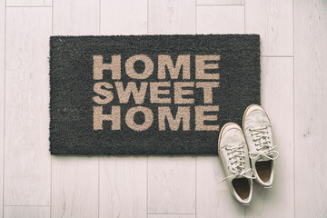Moving in new condo apartment Home sweet home text doormat at house entrance with women's sneakers...