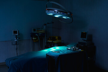 dark operating room with light shine on bed and medical equipment