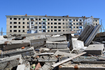 blocks and fittings from a destroyed house against the background of an abandoned building with empty windows