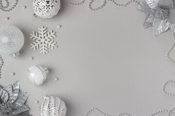 Holiday frame made silver and white shiny christmas decorations on grey background. Happy Christmas, Xmas and New Year concept. Top view, Flat lay, Copy space