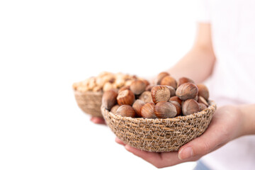 Close-up of a plate of hazelnuts and macadamia nuts in female hands.