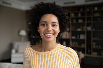 Happy pretty young African American woman in casual home head shot portrait. Millennial curly...