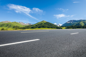 Asphalt highway and mountain under blue sky.