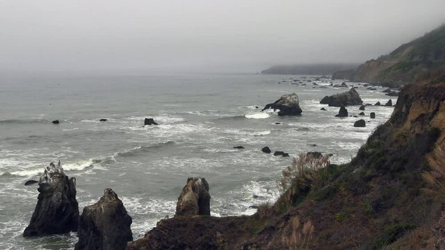 A California Sea Cliff on the Northern Coast Near Jenner, California, with Waves Pounding the Beach and Breaking Rocks with its Power as the Water Splashes over coastal rocks eroding the Mountain