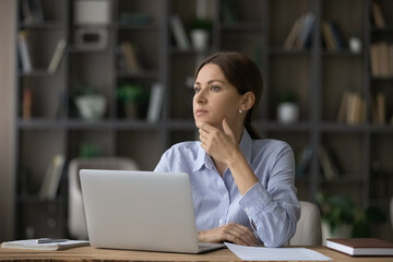 Attractive woman deep in thoughts sit at workplace near laptop. Pensive business lady thinking over...