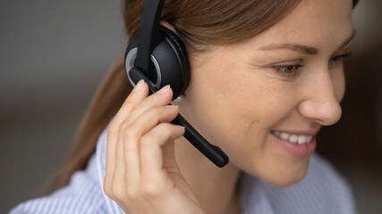 Smiling female telesales agent sell products services remotely working wear wireless headset with microphone close up. Call center operator face, counselling, consultation, contact customers concept