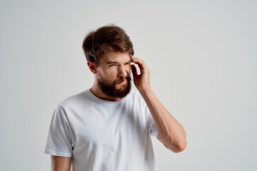 bearded man holding his head pain stress emotions light background