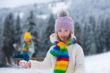 Cute children boy and girl playing on a winter walk in nature. Portrait of happy little kids wearing winter clothes.