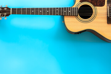 Obraz premium Acoustic guitar on a blue background, top view, copy space.