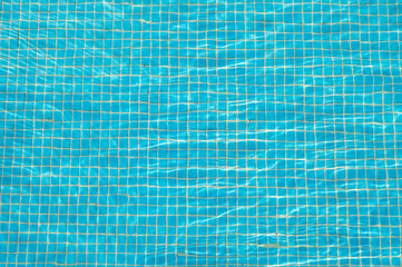 Blue pool water with sun glare, background and texture of water with mosaic tiles