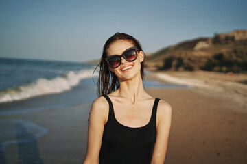 woman walks along the sandy shore in a black swimsuit sun tropics