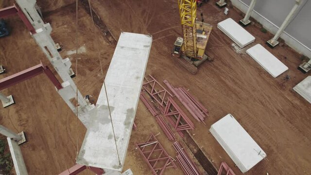 Aerial view. A heavy crane at a construction site is lifting iron concrete slabs.