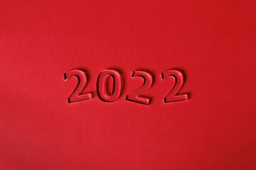 Fototapeta na wymiar Photo of numbers 2022 made of volumetric transparent acrylic glass on a red background. Selective focusing.