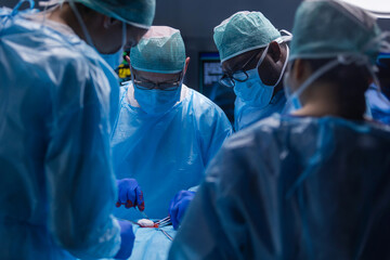 Multiracial team of professional medical surgeons performs the surgical operation in a modern hospital. Doctors are working to save the patient. Medicine, health, cardiology and transplantation.