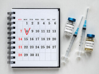 Syringes, injection vials and a calendar page lying on the table. Close-up, indoors, top view. Day light, studio photo. Healthcare concept