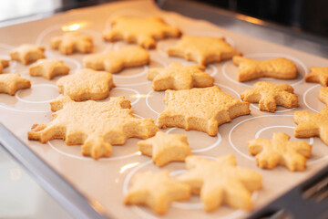 Baking tray with ginger Christmas cookies snowflakes in the oven.