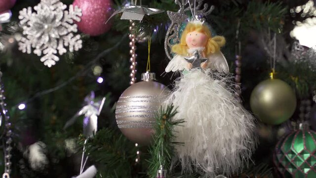 balls and toys on the Christmas tree. white angel girl in the form of a toy on a christmas tree and a flashing garland